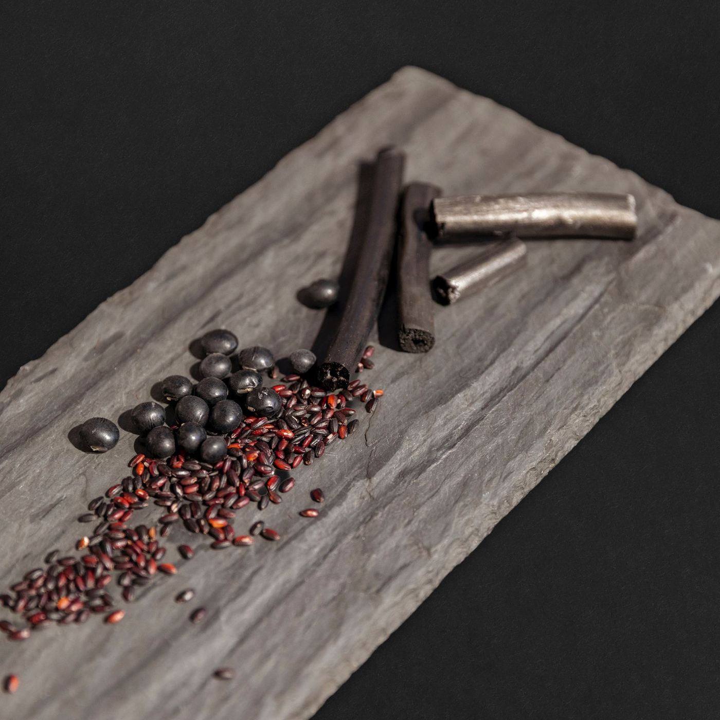 Hemp charcoal sticks, black soybeans and black rice on slate