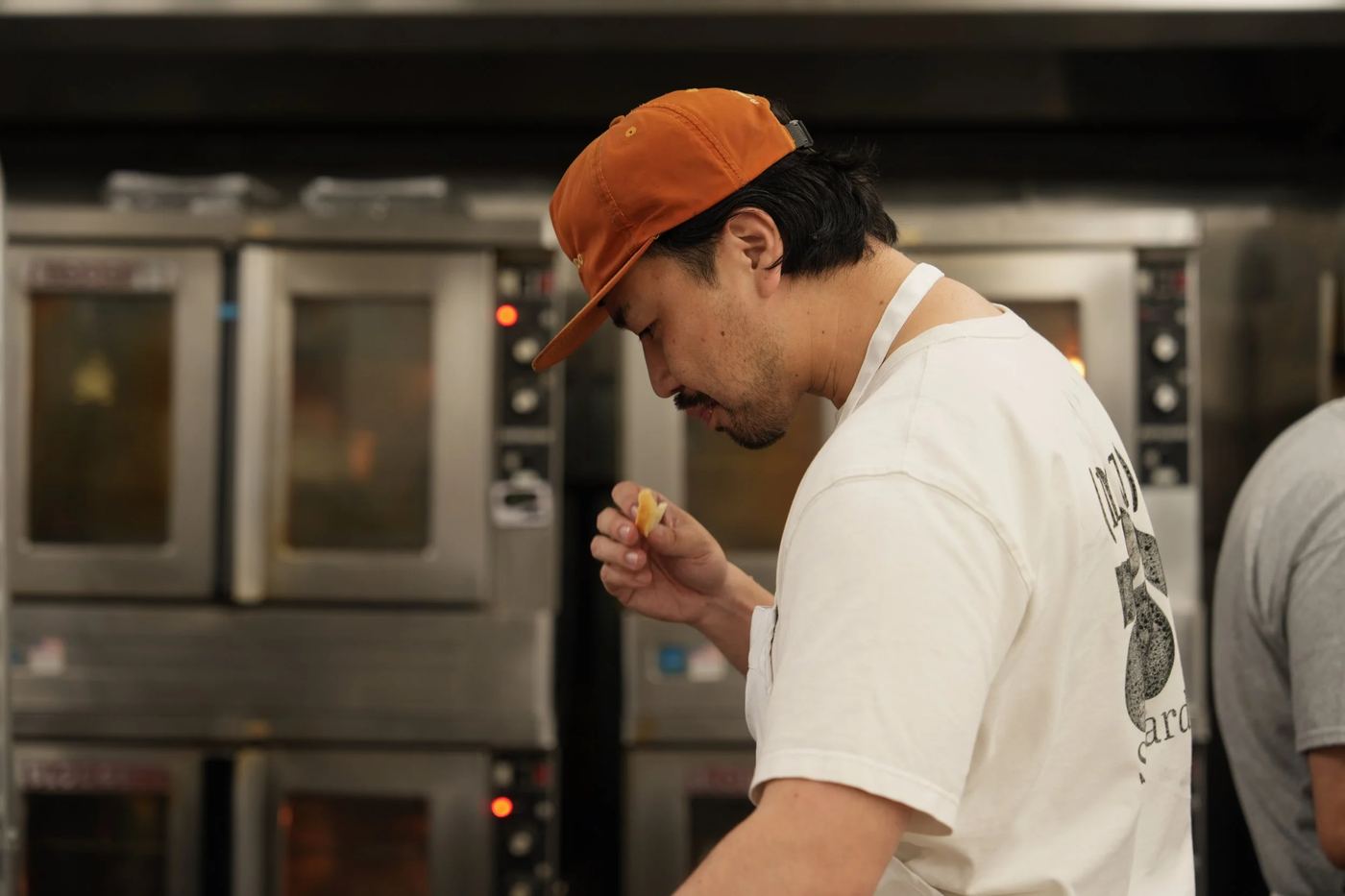 Hisashi Murakami tasting bread in front of the bakery ovens