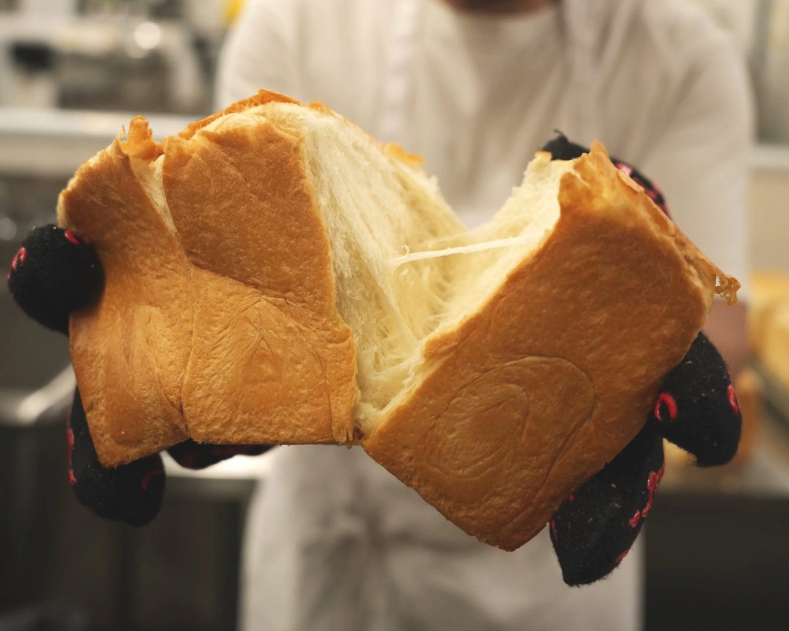 A (mu) Standard shokupan loaf pulled apart in oven mitts, showing its soft, stretchy crumb