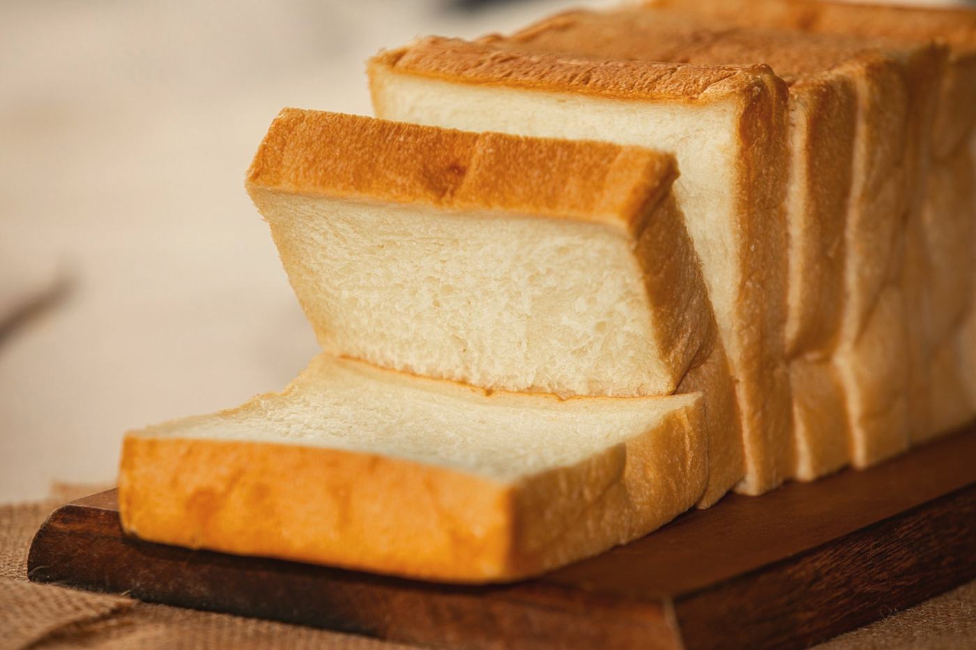 Thick slices of square white milk bread fanned out on a wooden board