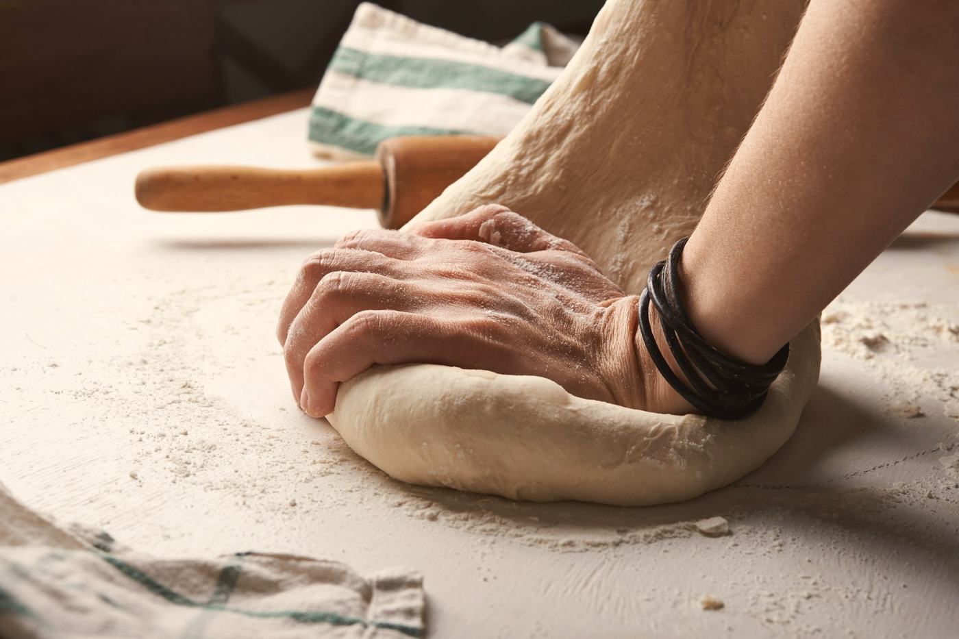 A hand kneading dough on a floured counter