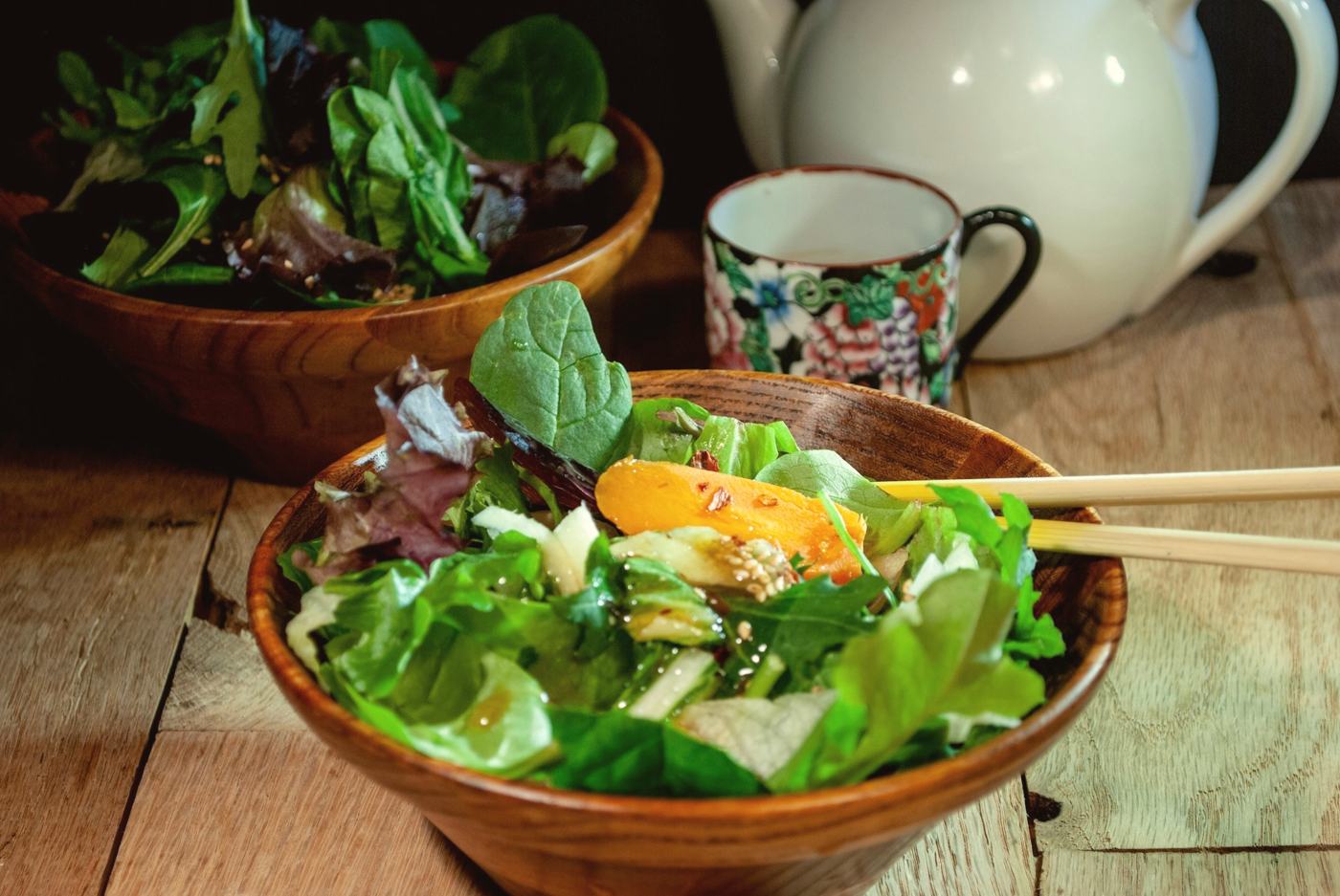 A dressed green salad in a wooden bowl
