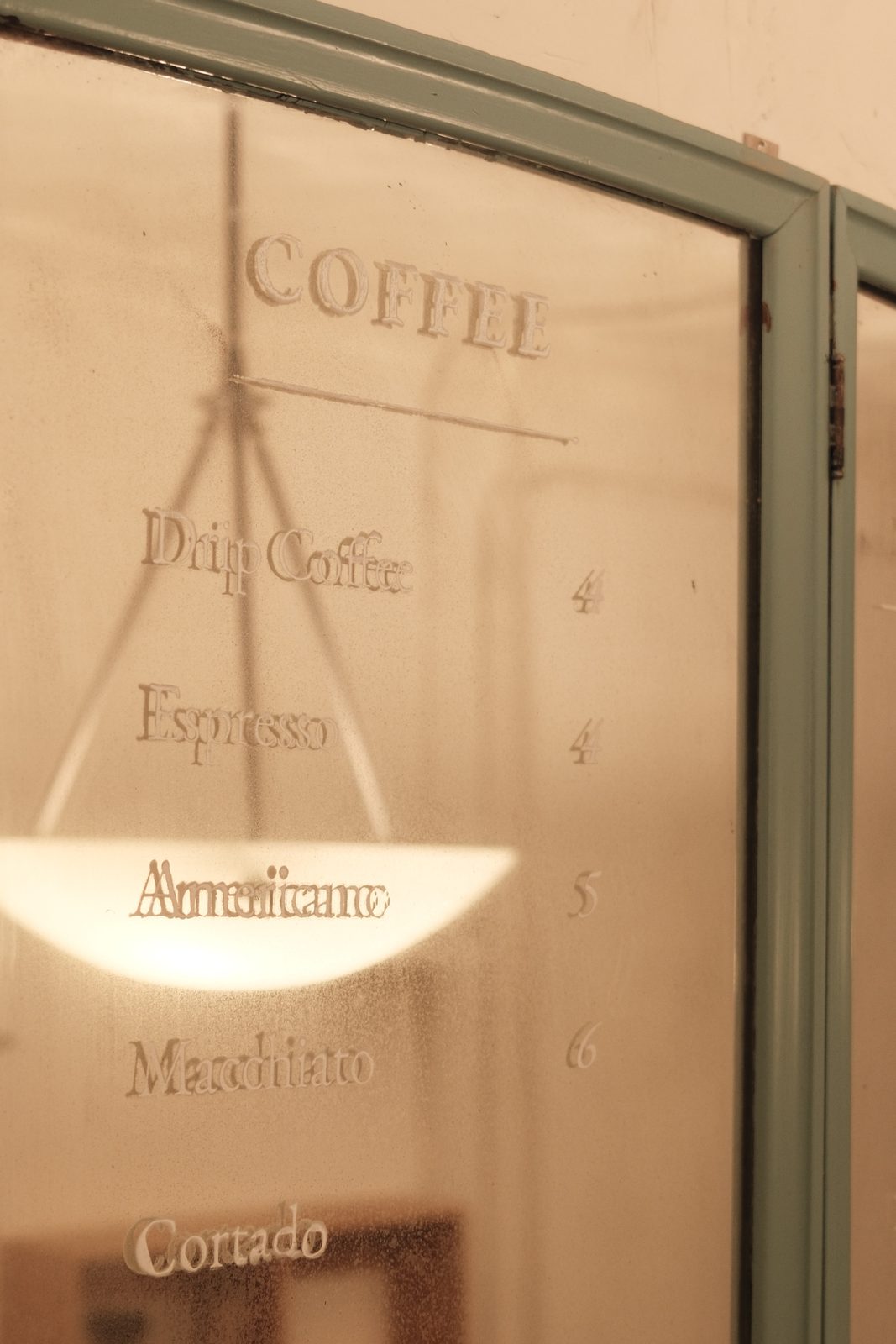 The coffee menu etched into the antique mirror at the shop counter